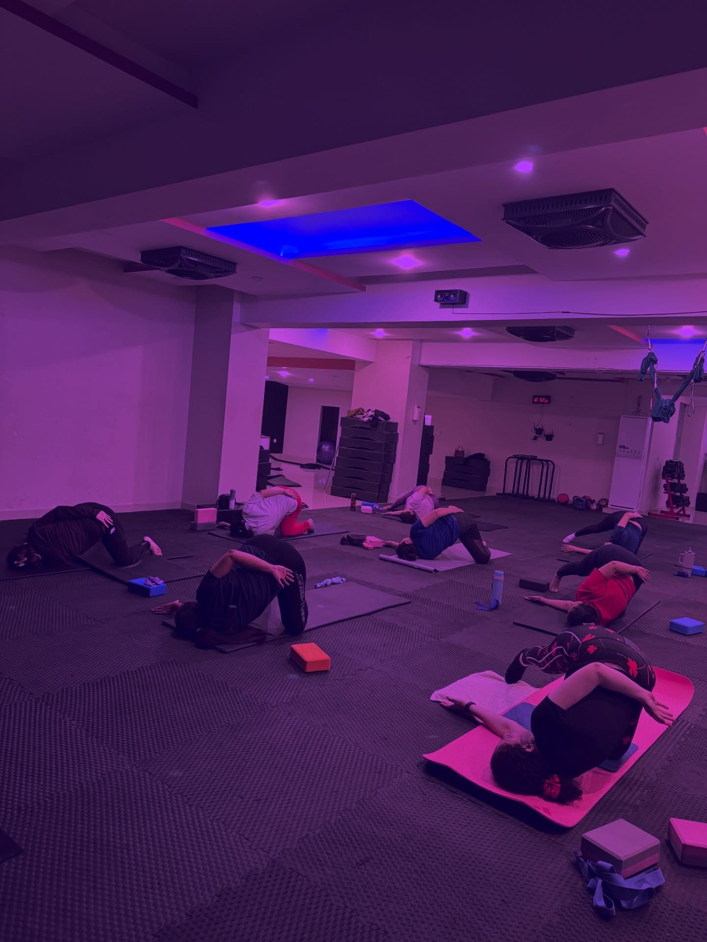 Students practicing yoga in a room with ambient purple lighting